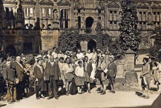 Black and white archive photo of a group of people stood outside a stone hostel building