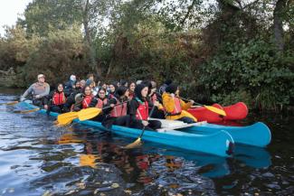 Grounp of people on a river in canoes