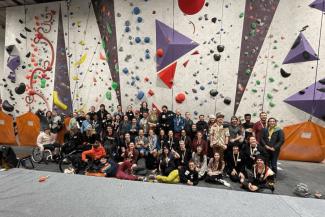 Group of people smiling in front of an indoor rock climbing wall