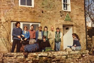 Group of people stood outside a stone hostel building