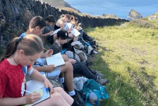 Group of children drawing on notepads in a field