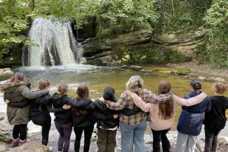 Group of young people near waterfall hugging