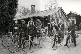 Black and white archive photo of a group of cyclists outside a wooden hostel building