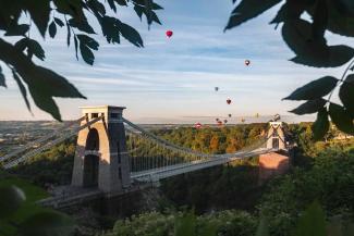 Hot air balloons flying over a suspension bridge