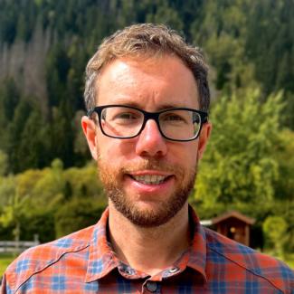 Man wearing glasses and a orange and blue checked shirt