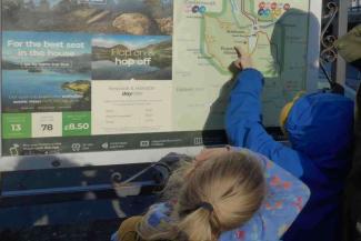 Two children pointing at a bus route map