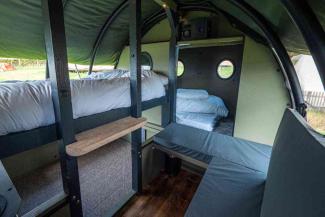 Inside a canvas Landpod with two bunk beds and a seating area