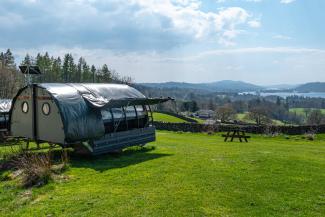 Glamping Landpod on a grass field overlooking a lake