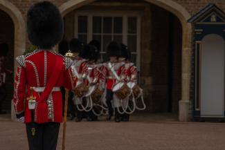 Guardians wearing tall black hats and red coats outside Buckingham Palace