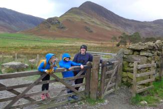 Man and two children stood at a gate in the countryside