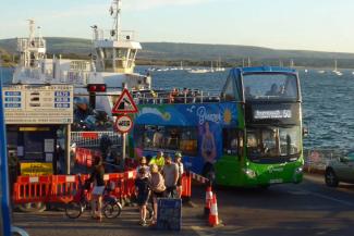 Blue open-top bus with the sea in the background