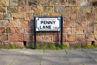 Street sign that reads "Penny Lane" in front of a brick wall