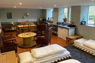 Studio room with futon beds, armchairs and kitchen cupboards