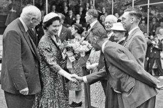 Black and white archive photo of a man bowing while shaking hands with the Queen