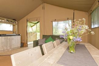 Inside a canvas tent with a vase of flowers on top of a dining table