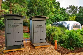 Wooden shower and lav shacks next to an Airstream caravan