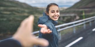 Smiling woman walking with hand held out