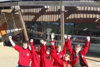 Group of school children smiling outside a building