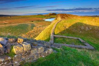 Sunset over a long stone wall structure surrounded by countryside