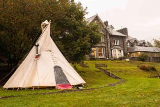 Canvas tipi tent outside a stone hostel building