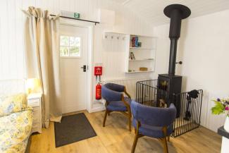 Spacious room with a bed, chairs and woodburning stove