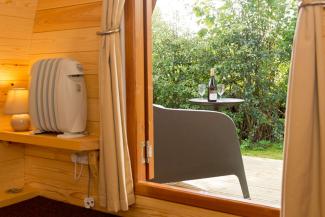 Inside a wooden camping pod with a door open onto trees