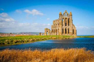 Water running past some grand abbey ruins