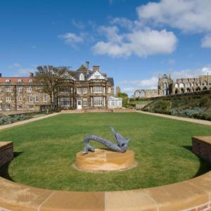 Large green lawn with a dragon statue and mansion building