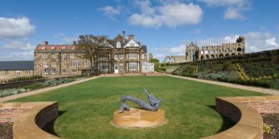 Large green lawn with a dragon statue and mansion building