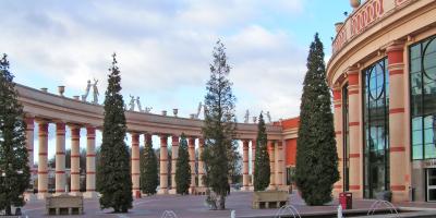 Large shopping centre exterior with stone columns and surrounding trees