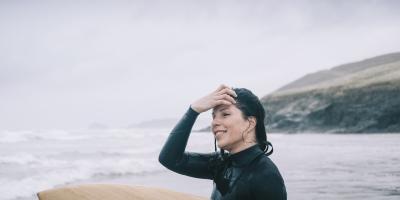 Watersports at Lizard Point, woman with surfboard looking out to sea