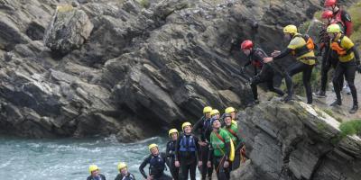 Group of people Coasteering on the Cliffs in Newquay, Cornwall