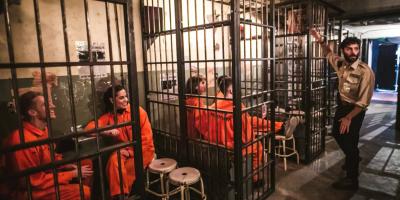 Groups of adults wearing orange jumpsuits behind bars