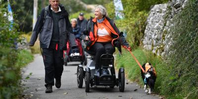 Accessible walking route from YHA Malham Man walking alongside a woman in a motorised wheelchair and a dog on a lead