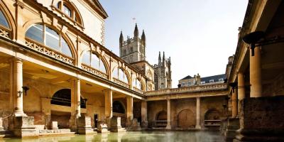 Open-air Roman spa bath surrounded by historic buidlings including a cathedral