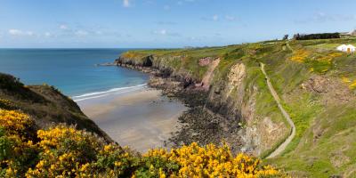 View of a beach surrounded by green hills looking out to the sea