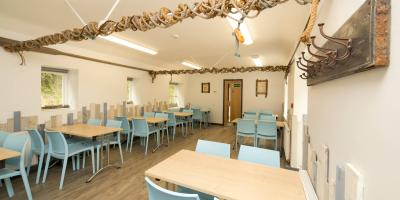 Room containing wooden tables and blue plastic chairs