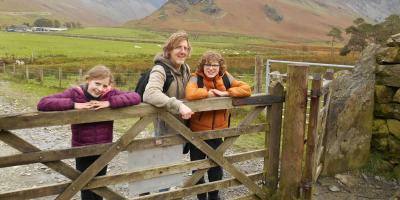 Dad and two children leaning on a wooden gate in the countryside