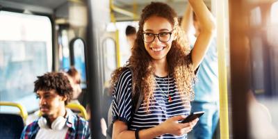 Young woman standing on a bus holding a mobile phone