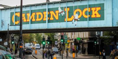 Metal industrial bridge painted in blue and green with the words Camden Lock