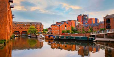 Large canal with boats surrounded by tall brick buildings