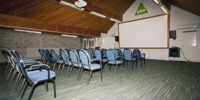 Large room with rows of chairs and a projector screen