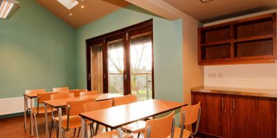 Room with blue painted walls containing rows of tables and chairs