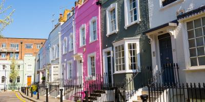 Row of terraced houses painted in different shades of pink, purple and blue