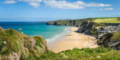 Green cliffs overlooking a beach and blue sea in the sunshine