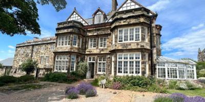 Large mansion building with stone walls and white wooden window frames