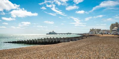 Pebbled beach overlooking the sea with a pier in the distance