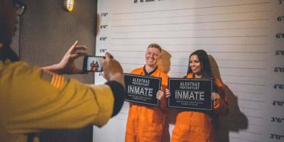 Person taking a photo of two people in orange jumpsuits