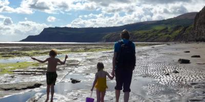 Dad and two children walking on wet sand on a beach