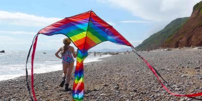 Young girl running on a beach with a rainbow kite